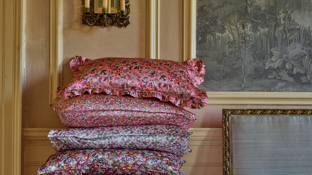 stack of liberty print silk pillowcases coco and wolf photographed in panelled drawing room