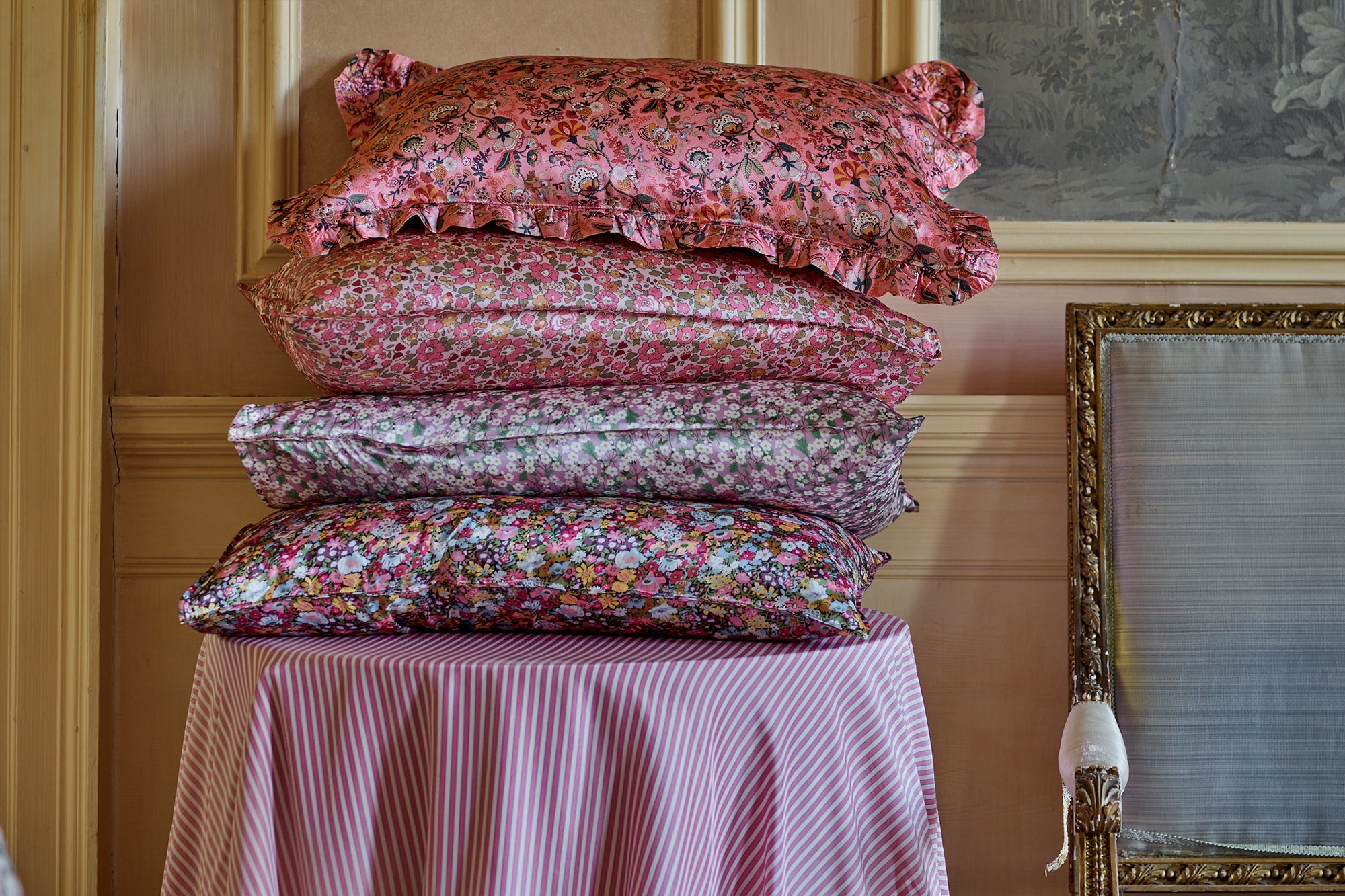 stack of liberty print silk pillowcases coco and wolf photographed in panelled drawing room