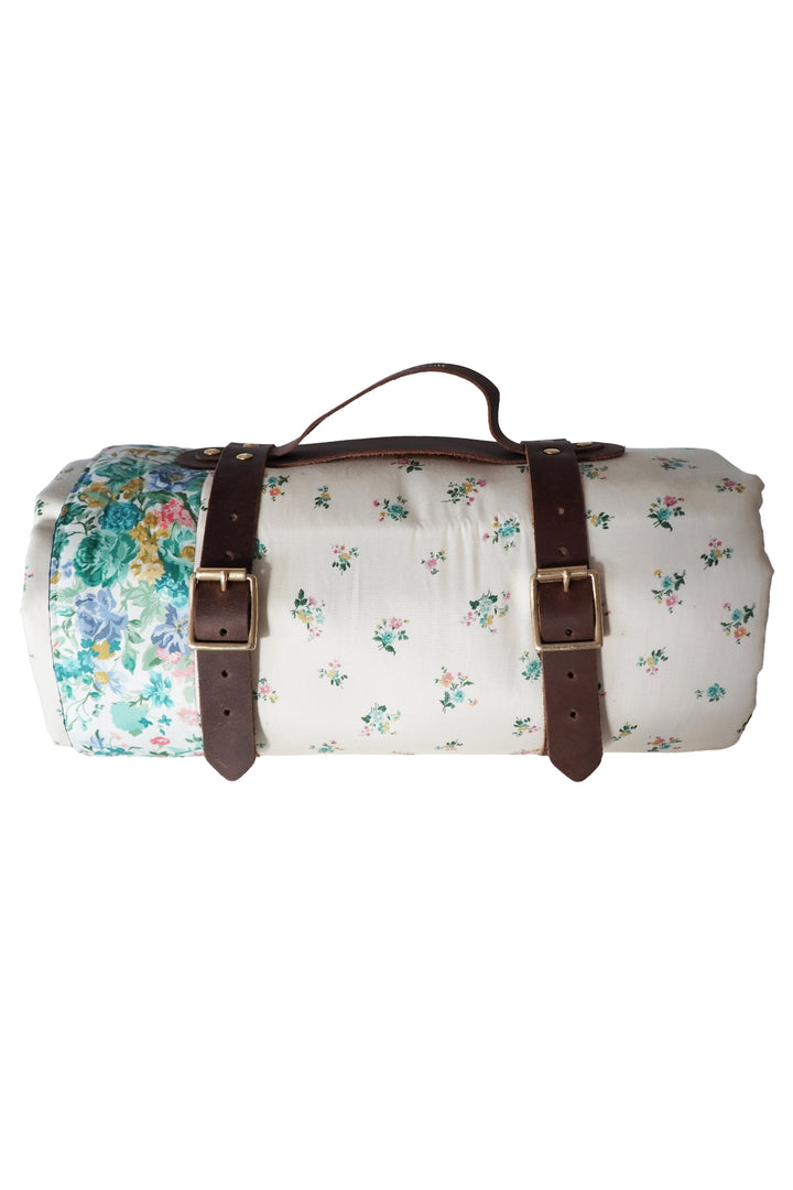 Floral-patterned duffel bag with brown leather straps on a white background